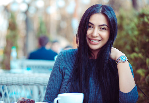 Portrait of a beautiful indian woman smiling outdoors on a terrace of a coffee shop restaurant