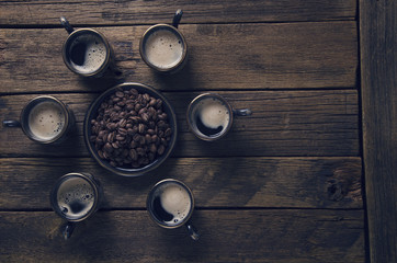cups with hot coffee and grains on the board surface