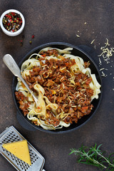 Dinner. Bolognese sauce with tagliatelle and parmesan cheese on a brown concrete background.