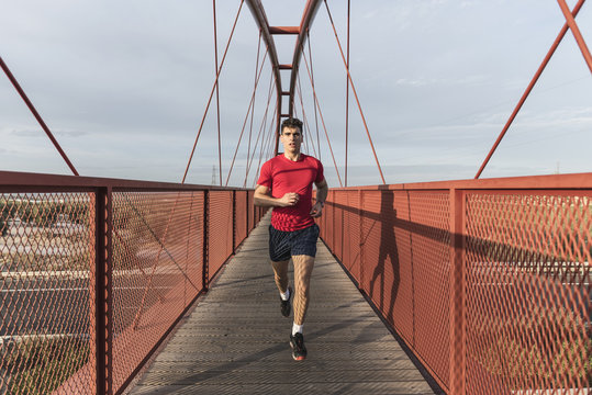 Man in red running on red bridge in sunset