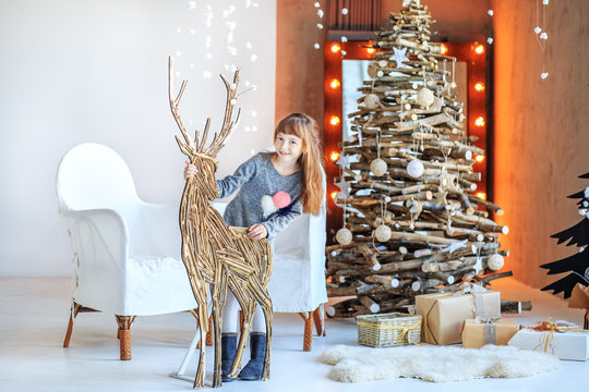 A little girl is standing near a Christmas reindeer. Concept Happy Christmas, New Year, holiday, winter, childhood.