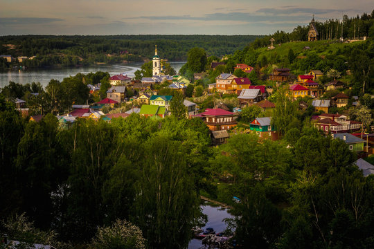 Village houses with a church on a hill on the river bank