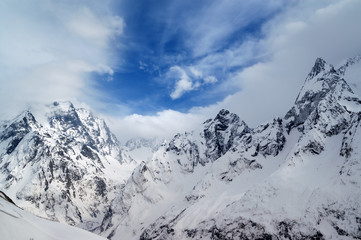 Fototapeta na wymiar Gray high mountain peaks covered with ice
