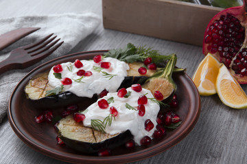 baked eggplants on a plate with cream cheese and pomegranate seeds
