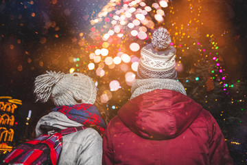 Fototapeta premium Snowy evening at traditional Christmas market, Couple wearing warm winter clothes