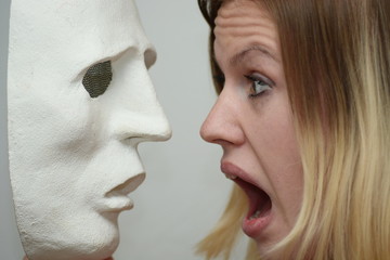 Young blonde girl holding a white theatrical mask