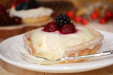Blackberry raspberry panna cotta tart on white plate with silver spoon. Delicious christmas dessert.  Texture of cake. Closeup.