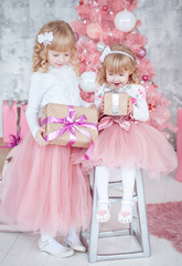 Девочки с подарочными коробками возле розовой ёлки 