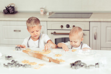 Obraz na płótnie Canvas Happy family funny brothers kids are preparing the dough and bake cookies in the kitchen