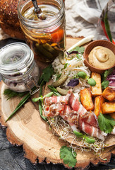 rustic composition: Herring fillets, lard, pickles, baked potatoes and sauerkraut on a bread plate