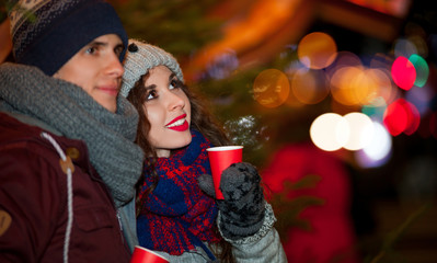 Couple with hot drinks having fun on Christmas market
