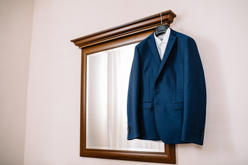 Fototapeta na wymiar Blue wedding suit on hangers for groom at room.