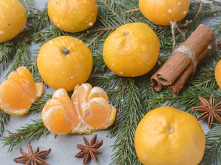 Fresh tangerines with branches of Christmas tree, star anise cinnamon on gray concrete background