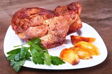Juicy pork neck chops are grilled with potatoes on a white plate.