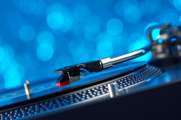 Turntable vinyl record player. Sound technology for DJ to mix & play music. Vintage vinyl record player on a background decorations for a party, bright disco lights. Needle on a vinyl record          