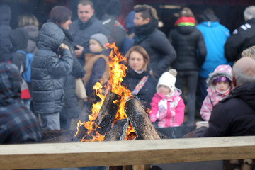 Dorośli i dzieci na kempingu wokół płonącego ogniska w Opolu na rynku. - obrazy, fototapety, plakaty