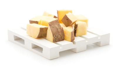 Chopped sweet potato pieces on pallet isolated on white background.
