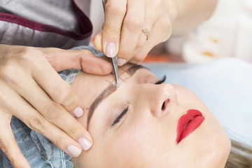 Fototapeta na wymiar Correction of eyebrows in the beauty salon