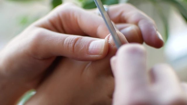The girl does a pedicure at home. A woman is peeling her nails on her feet, close-up