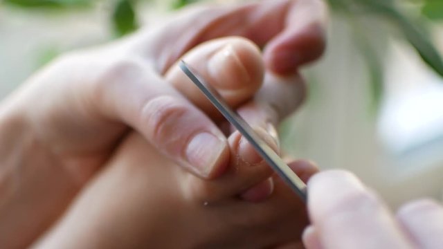 The girl does a pedicure at home. A woman is peeling her nails on her feet, close-up