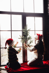 Decorating home for Christmas. Couple kids Little girl and boy  in santa klaus hat make decor for...