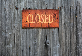 Rusty metal sign with the word closed.