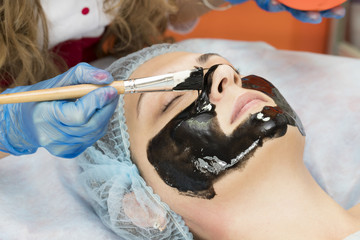 Naklejka premium Process cosmetic mask of massage and facials in beauty salon