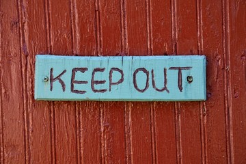 Keep out warning sign over old rustic wooden textured surface.