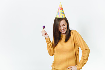 Beautiful caucasian fun young happy woman in yellow clothes and birthday party hat with brown long hair, playing pipe, celebrating and enjoying holiday on white background isolated for advertisement.