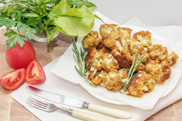 Fried cauliflower in batter on a white plate with white napkin. Close-up