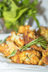 Fried cauliflower in batter on a white plate with white napkin. Close-up