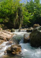 Naklejka premium Mały wodospad wśród skał na górskiej rzece.