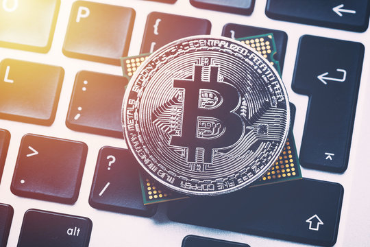 Bitcoin cryptocurrency with processor on keyboard. Close up image with sunlight