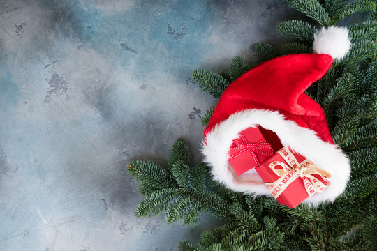 Christmas evergreen tree and Santa Claus red and white hat with gifts. copy space on gray background
