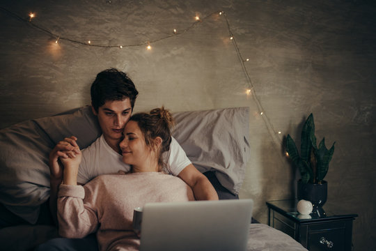 Romantic young couple with laptop on bed