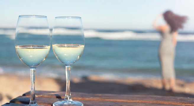 Two white wine wineglasses over sea background.Tropical vacation on beach.