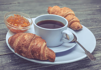 Croissant with orange jam and a cup of tea. Continental breakfast concept. Selective focus