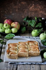 On the stand is a curd cake with apples, in slices. Fresh apples