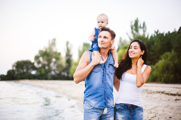 beautiful young family on vacation with baby. The father holds the blonde girl in her arms, and the brunette's mother hugs her husband. The concept of a family beach holiday summer near the sea