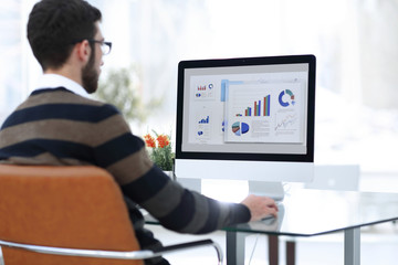 businessman analyzing graphs on computer at desk