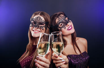 Girls celebrating New Year's eve drinking champagne on masquerade party