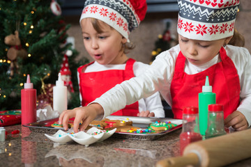 Twin girls in red making Christmas cookies