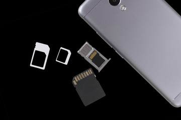 Adapters on a SIM card from larger to nano-sim with a SIM card in the slot next to the phone at an...