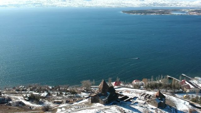 Aerial drone flight over the beautiful lake Sevan and Church with flying birds, Armenia, Caucasus. 