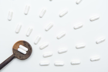 White tablets on a medicine dose spoon, with tablets across the table