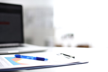 Laptop computer with folder on desk , two businesspeople standing in the background