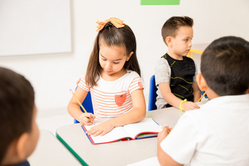 Hispanic preschool girl working in class