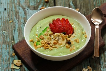 Avocado Smoothie Breakfast bowl with granola chia banana and strawberry, selective focus