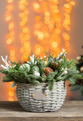 Beautiful Christmas composition in a wicker basket on wooden boards. Preparation for holidays concept. Flower shop is a master work of a professional florist. copy space. lights garland