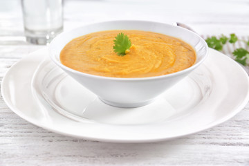 Plate with bowl of homemade lentils creme soup on table